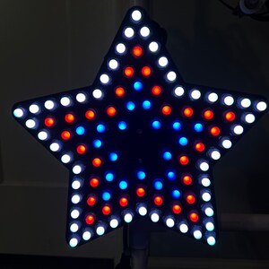 May include: A star-shaped light fixture with white, red and blue LED lights. The lights are arranged in a circular pattern.