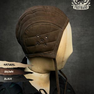 May include: A brown quilted cap with a rounded crown and side ties. The cap features a five-eyelet ventilation pattern on the side. A logo in the top right corner displays an octopus illustration with the text FREYHAND. Color swatches show NATURAL, BROWN, and BLACK.