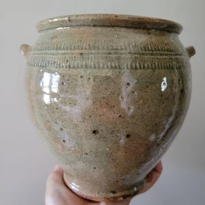Vaso de grés vidrado artesanal com detalhes texturizados e esmalte verde rústico.