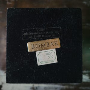 May include: A black velvet box with a gold label that reads "BOMBAY" and a smaller green label that reads "2001 XX MADE IN CHINA".
