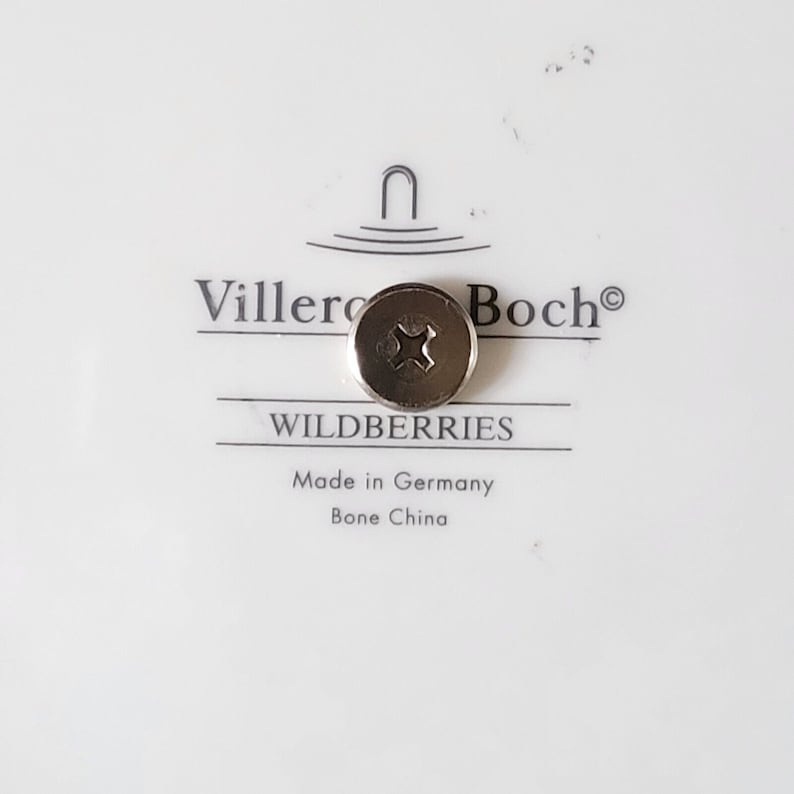May include: A white porcelain plate with a silver screw in the center. The plate has the text "Villeroy & Boch" and "Wildberries" printed on it. The text "Made in Germany Bone China" is also printed on the plate.