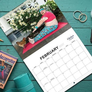 May include: A 2017 wall calendar titled Chicken Daddies featuring a photograph of a person in a pink crop top and patterned leggings stretching on a red mat with a chicken. Accessories include Jazzercise VHS tapes, pink dumbbells, and a cassette.
