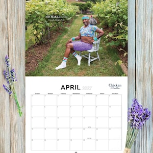 May include: A wall calendar for April 2027 titled Chicken Daddies featuring a photograph of a person sitting on a chair in a vineyard wearing a floral crop top, purple patterned shorts, a blue headband, and white socks with striped cuffs.