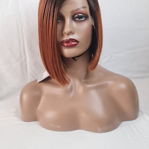 Könnte beinhalten: Eine kurze, gerade, rotbraune und braune Ombre-Perücke mit Seitenscheitel. Die Perücke sitzt auf einem Mannequin-Kopf.