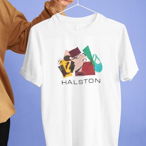 May include: White t-shirt featuring a colourful abstract design with the word "HALSTON" printed in black below the design.