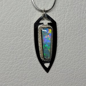 Può includere: Una collana d'argento con un ciondolo a forma di scudo, con un opale multicolore incastonato in una cornice d'argento e oro.