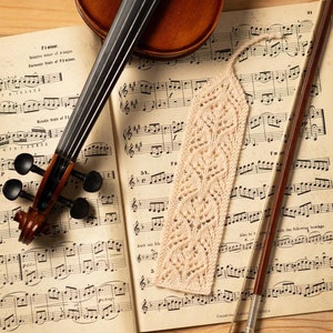 May include: A violin and bow lay on a sheet of music with a crocheted bookmark. The music sheet is open to a page with the title "F minor".