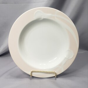 May include: A white porcelain soup bowl with a pink rim and a swirl design. The bowl is on a gold stand.