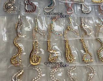 May include: A variety of rhinestone chains in different colors and styles, including gold, silver, and iridescent. The chains are arranged in rows on a clear plastic sheet with the word "COOSTOP" printed on it.