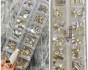 May include: A clear plastic storage box with 12 compartments filled with iridescent rhinestones and crystals. The box is labeled "CocoShop".