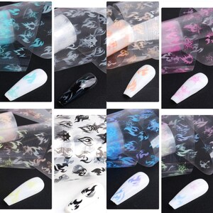 K&ouml;nnte beinhalten: Set mit 10 Nagelfolien mit Flammenmuster. Die Folien sind transparent mit verschiedenen schillernden Ausf&uuml;hrungen, darunter Blau, Rosa, Schwarz und Wei&szlig;.