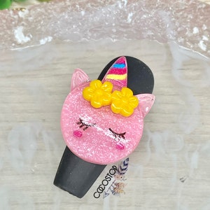 May include: Pink unicorn hair clip with yellow flowers and a rainbow horn. The clip is 16mm wide and 21mm long. Size 16mm W x 21mm L.
