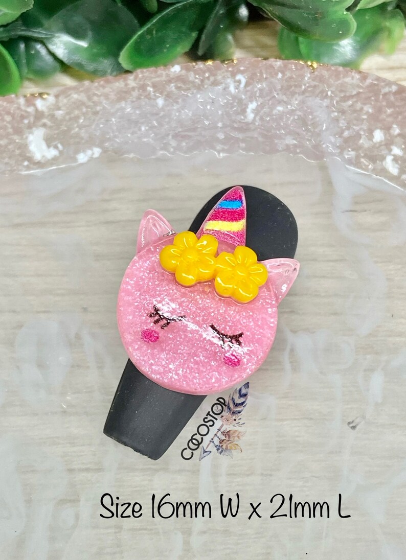 May include: Pink unicorn hair clip with yellow flowers and a rainbow horn. The clip is 16mm wide and 21mm long. Size 16mm W x 21mm L.