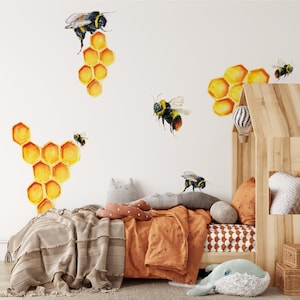 May include: A white wall with a brown wooden bed frame and a white and orange patterned bedspread. The wall is decorated with bee and honeycomb decals.
