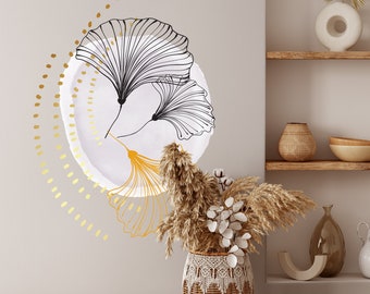 May include: A white circle with a black and gold stylized ginkgo leaf design. The circle is surrounded by a ring of gold dots. A dried flower arrangement in a woven basket sits in front of the design.