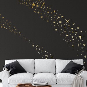 May include: A white sofa with black cushions in front of a black wall with a gold star pattern. The stars are arranged in a curved line.