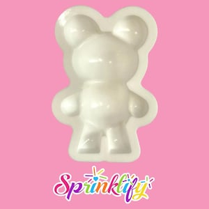 Może przedstawiać: Biała forma w kształcie misia do majsterkowania. Forma ma gładką powierzchnię i jest zaprojektowana z głową, ramionami i nogami misia. Słowo "Sprinklify" jest napisane kolorową, kursywą u dołu obrazu.