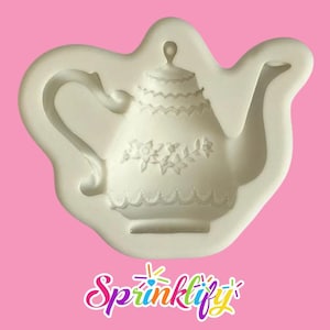 Puede incluir: Un molde de silicona blanco con forma de tetera. El diseño de la tetera presenta detalles florales y de encaje. El asa y el pico están claramente definidos. La palabra "Sprinklify" está escrita en una fuente cursiva colorida en la parte inferior de la imagen.