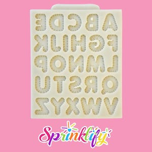 May include: A white silicone mold with the alphabet letters A through Z. The letters are in a stitched font. The mold is on a pink background with the Sprinklify logo in the bottom corner.