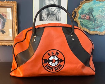 Pode incluir: Bolsa de viagem vintage A&W Root Beer laranja e preta com um logotipo branco e um design de seta. A bolsa tem uma alça preta e um fecho de correr.