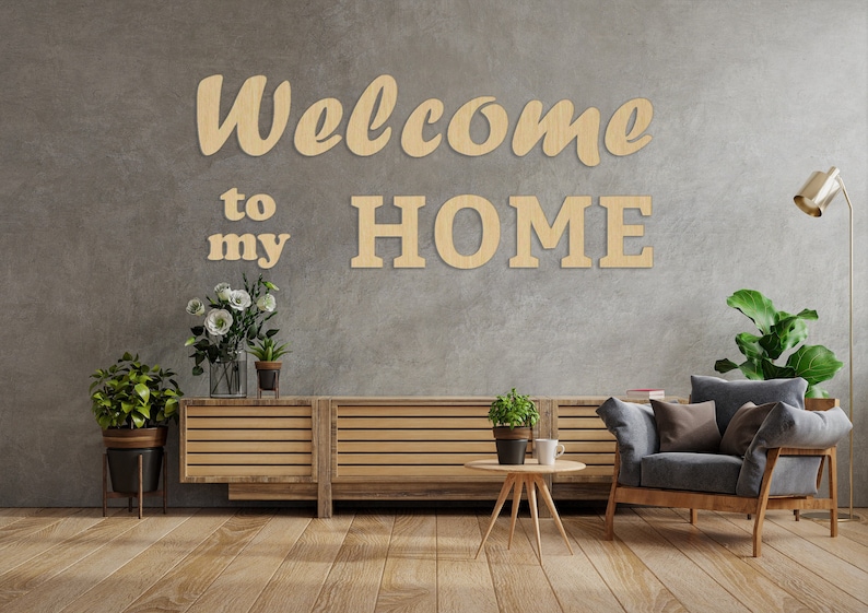 May include: Wooden wall decor with the words "Welcome to my HOME" in a living room setting with a couch, a coffee table, and plants.