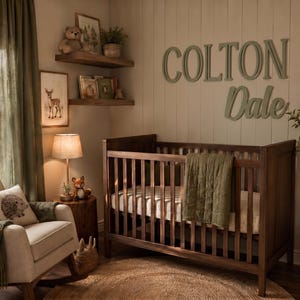 K&ouml;nnte beinhalten: Ein Kinderzimmer mit einem dunkelbraunen Gitterbett mit gr&uuml;ner Steppdecke, einem beigen Schaukelstuhl mit Igelkissen und h&ouml;lzernen Wandbuchstaben, die COLTON Dale bilden. Der Raum enth&auml;lt Wandregale, eine Lampe und eine Topfpflanze.