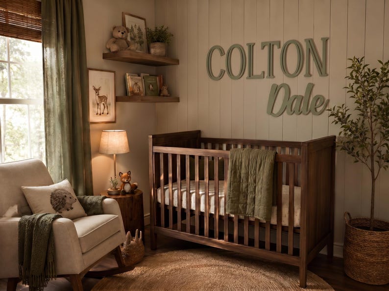 K&ouml;nnte beinhalten: Ein Kinderzimmer mit einem dunkelbraunen Gitterbett mit gr&uuml;ner Steppdecke, einem beigen Schaukelstuhl mit Igelkissen und h&ouml;lzernen Wandbuchstaben, die COLTON Dale bilden. Der Raum enth&auml;lt Wandregale, eine Lampe und eine Topfpflanze.