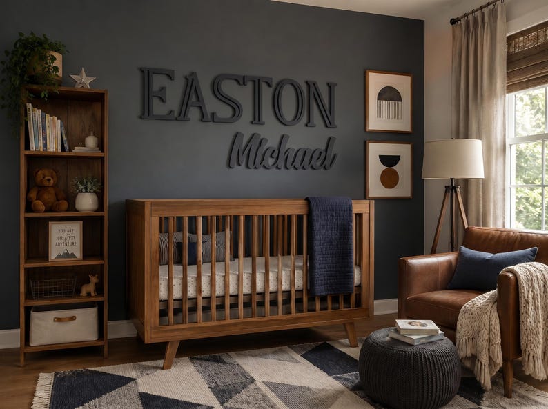 K&ouml;nnte beinhalten: Ein h&ouml;lzernes Kinderbett mit vertikalen St&auml;ben und einer dunkelblauen Decke, platziert in einem Raum mit einem hohen Holzregal, einem braunen Ledersessel, einer dunkelgrauen Wand mit dem Namen EASTON Michael in gro&szlig;en Buchstaben und einem geometrischen Teppich.