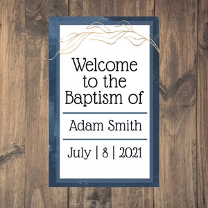 Peut inclure: Une pancarte bleue et blanche avec des accents dorés annonçant le baptême d'Adam Smith le 8 juillet 2021. La pancarte a un fond aquarelle et le texte "Welcome to the Baptism of Adam Smith July 8 2021" est imprimé en noir.