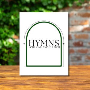 May include: A white rectangular card with the text "HYMNS FOR HOME AND CHURCH" in black, framed by a green arch and border. The card is set on a wooden surface with a brick wall and green foliage in the background.