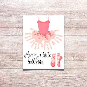 Puede incluir: Un traje de bailarina rosa hecho con huellas de manos, con el texto "Mommy's little ballerina" y un par de zapatillas de ballet rosas.