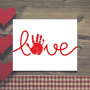 May include: A white card with the word "love" written in red cursive script. A red handprint is in the center of the word "love".