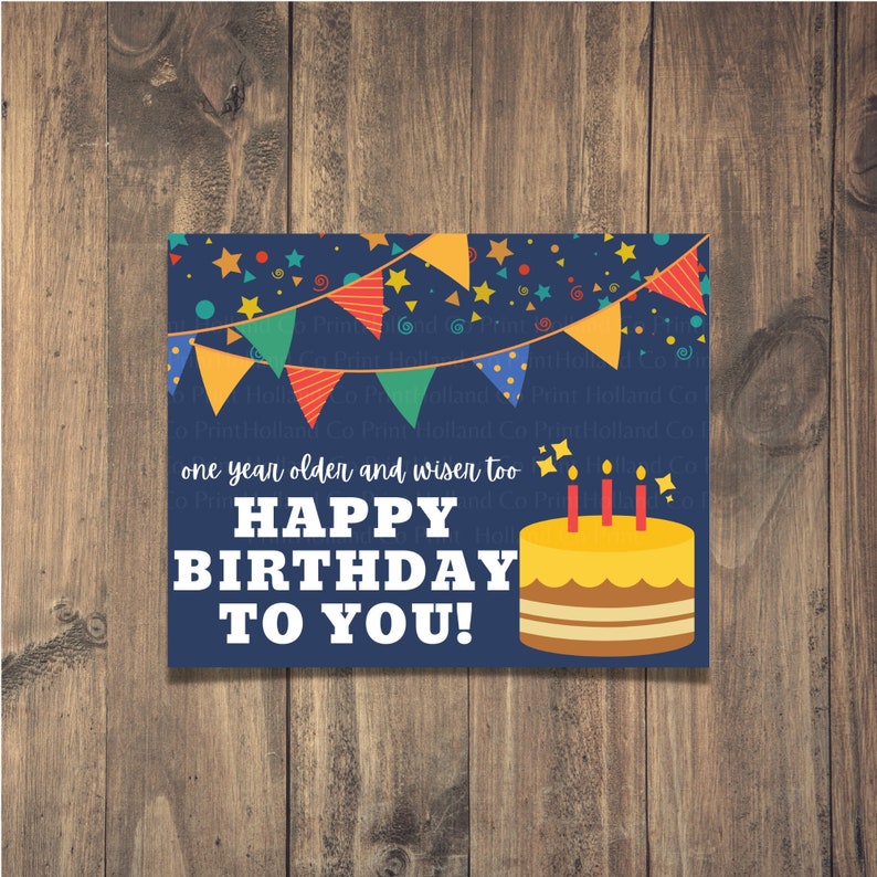 May include: A blue birthday card with colorful bunting, stars, and confetti. The card says "one year older and wiser too" and "HAPPY BIRTHDAY TO YOU!" with a yellow cake with three candles.
