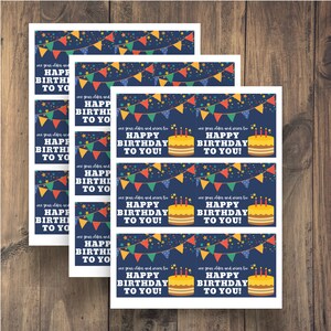May include: Printable birthday gift tags with a blue background, colorful pennant flags, stars, and a yellow cake with candles. The text reads "one year older and wiser too, Happy Birthday to you!"