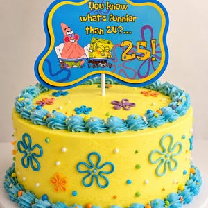 May include: A round yellow cake decorated with blue frosting swirls and blue flower shapes, topped with a blue sign featuring Patrick Star and SpongeBob SquarePants with the text: You know what's funnier than 24?... 25!