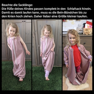 Ein Kind trägt einen ärmellosen Schlafsack mit Füßen und einem durchgehenden Reißverschluss. Der Schlafsack hat eine lockere Passform. Hier sieht man wie der Schlafsack durch die Bein-Bündchen gerafft wird. Text auf Deutsch gibt Größenhinweise.