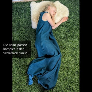 Tragebild mit einem Grundschulkind in einem Schlafsack mit Füßen. Zu erkennen ist, dass die Füße vollständig im Schlafsack verschwinden können. Der Text im Bild lautet: "Die Beine passen komplett in den Schlafsack hinein."