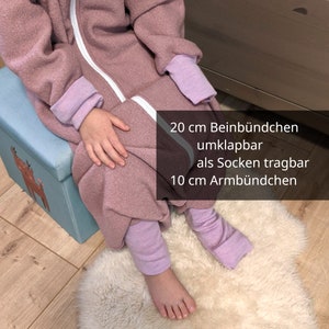 Könnte beinhalten: Ein Schlafsack mit Füßen und Bündchen. Der Text auf dem Bild lautet: "20 cm Beinbündchen, umklappbar, als Socken tragbar, 10 cm Armbündchen."
