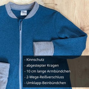 Detailansicht eines Schlafsack mit Füßen in der Farbe Petrol. Die Arm-Bündchen sind 10 cm lang. Der Kragen ist zusätzlich abgesteppt, damit er gut anliegt und nicht kitzelt. Der Reißverschluss hat 2 Zipper und ist damit auf 2 Wegen zu öffnen. Die Beinbünden können umgeklappt werden und damit kann der Schlafsack vollständig geschlossen werden.