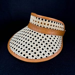 May include: A brown leather and woven straw sun visor with a wide brim.