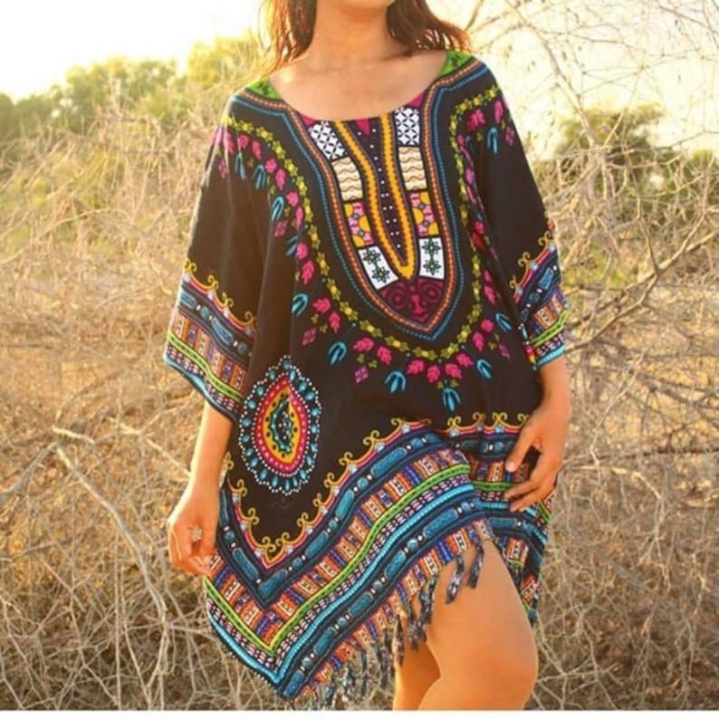 Puede incluir: Una kaftan negra con estampado colorido y flecos. La kaftan tiene cuello en V y mangas cortas.