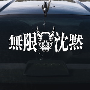 May include: A white vinyl sticker with a Japanese demon face and the text "無限 劣悪" on a black car window.
