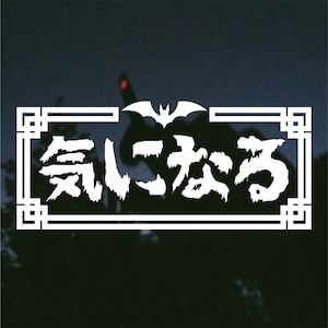May include: White rectangular sticker with Japanese text and a bat silhouette. The text, in a bold, stylized font, is framed by a white border with decorative corners. The background is a dark, blurred image of a hand.