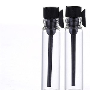 May include: Two clear glass bottles with black caps and droppers. The bottles are designed for holding and dispensing small amounts of liquid.