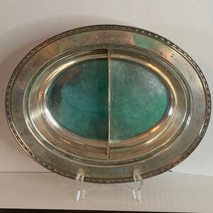 May include: A silver oval serving dish with a divided center section. The dish has a beaded edge and a green interior.