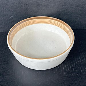 以下が含まれることがあります： 茶色の縁取りが付いた白い陶器のボウル。ボウルは斑点のある仕上げで、丸みを帯びた形をしています。