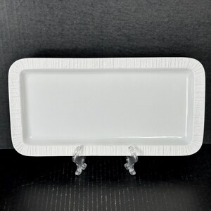 May include: White rectangular ceramic serving tray with a textured rim.