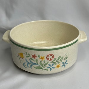 May include: A cream-colored ceramic bowl with a green rim and a floral design in shades of yellow, red, blue, and green.