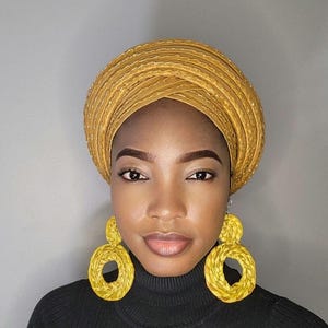 May include: A woman wearing a gold turban with a gold braided design and large gold hoop earrings.