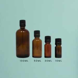 May include: Four amber glass bottles with black lids, lined up from largest to smallest. The bottles are labelled 100ml, 50ml, 30ml, and 10ml.